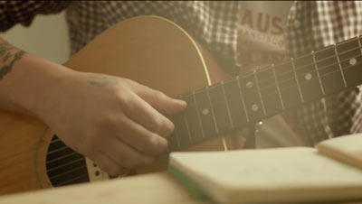 Nærbilde av hånd som spiller gitar. Lenke til video.